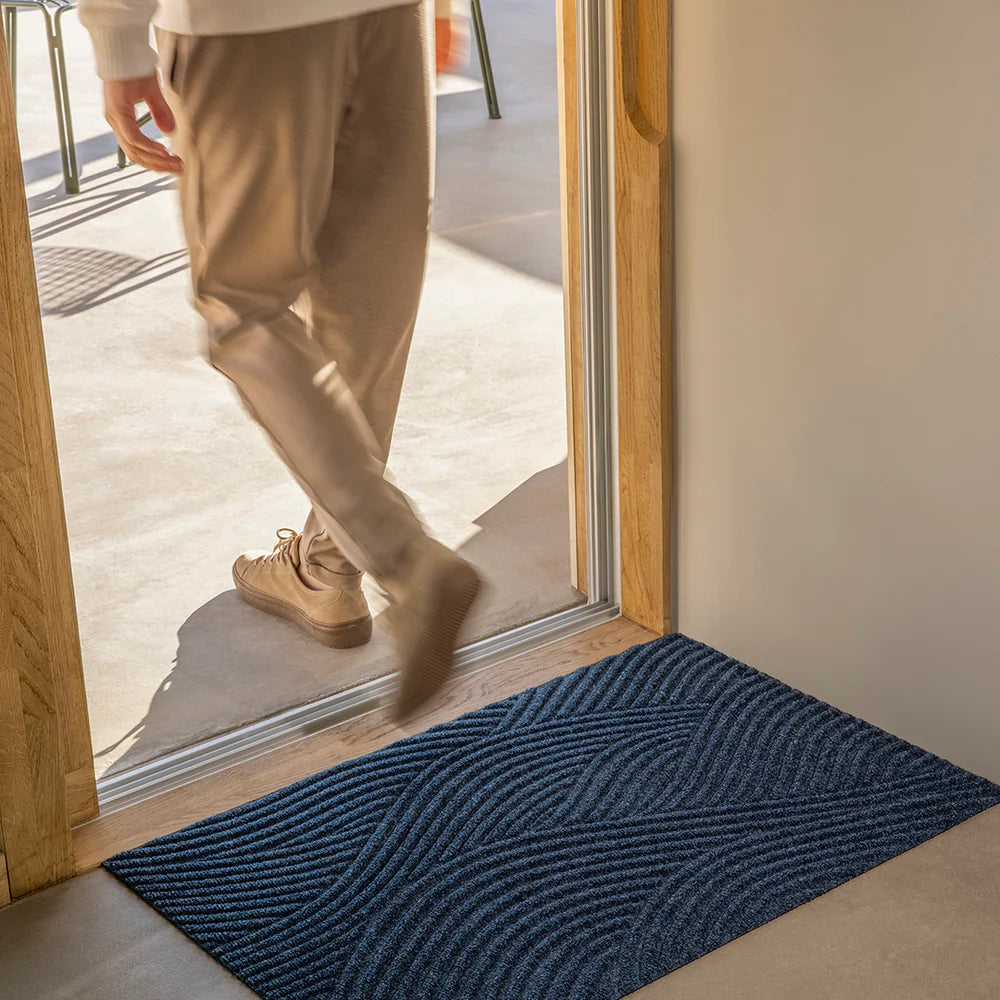 Heymat Sjo doormat with sea-inspired wave pattern, styled in coastal-inspired entryway with natural décor.