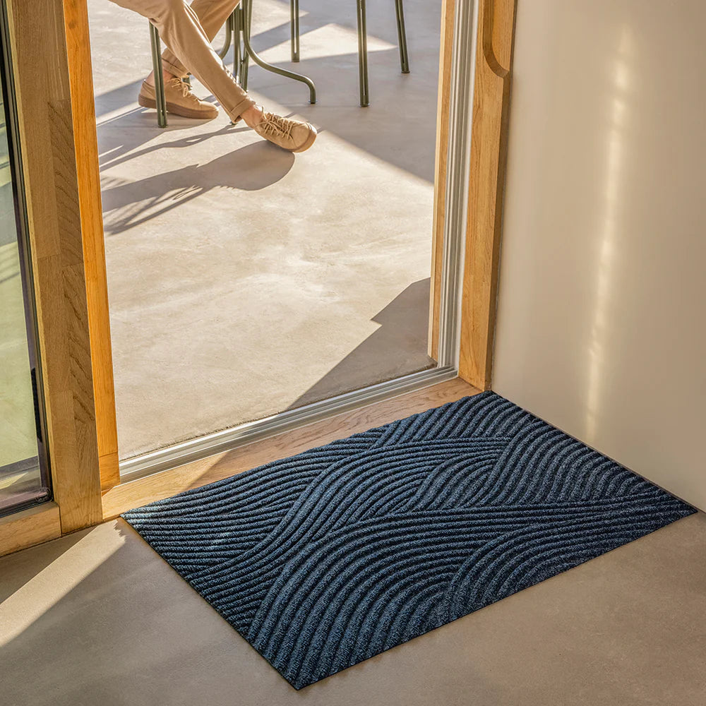 Heymat Sjo doormat with sea-inspired wave pattern, styled in coastal-inspired entryway with natural décor