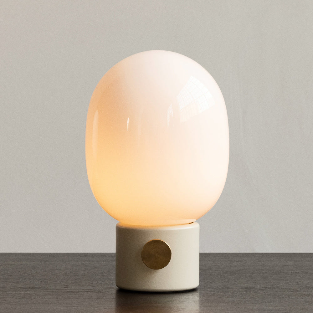 Audo Copenhagen JWDA Table Lamp in Alabaster white shown with lamp shade softly illuminated.