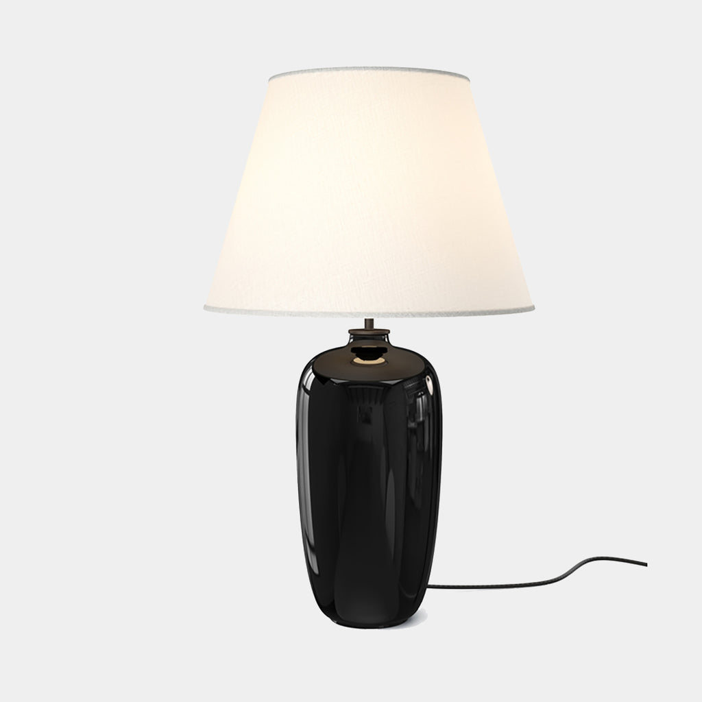 Torso Table Lamp by Audo Copenhagen with black ceramic base and linen shade on neutral background