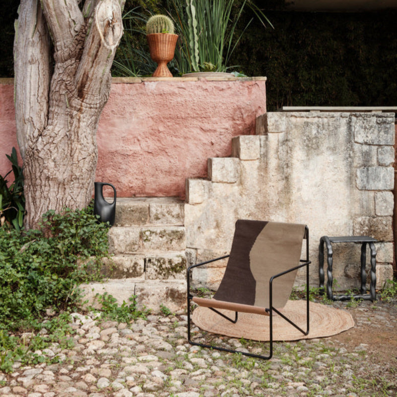 Small Eternal Rug from Ferm Living in round styled outdoors near stone wall and planters.