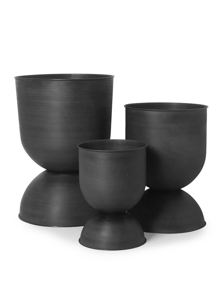 Ferm Living Hourglass Pots in Black shown in small, medium, and large sizes — sculptural matte iron planters with reversible hourglass design.