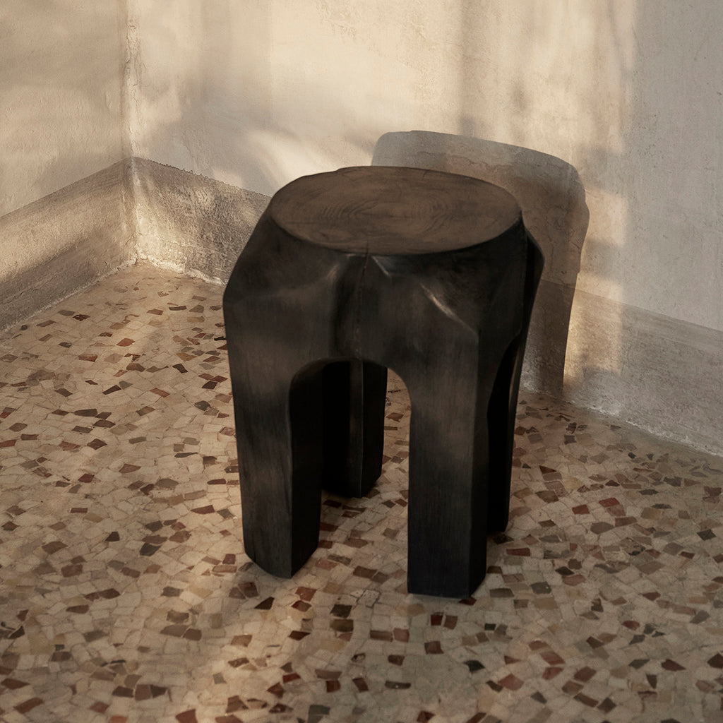 Ferm Living Root Stool shown near plaster wall and mosaic stone floor.