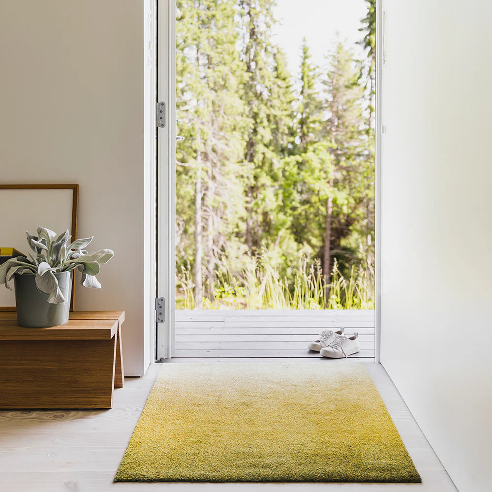 Heymat Dis Moss ombré doormat, styled with plants and wood accents in a nature-inspired entryway.