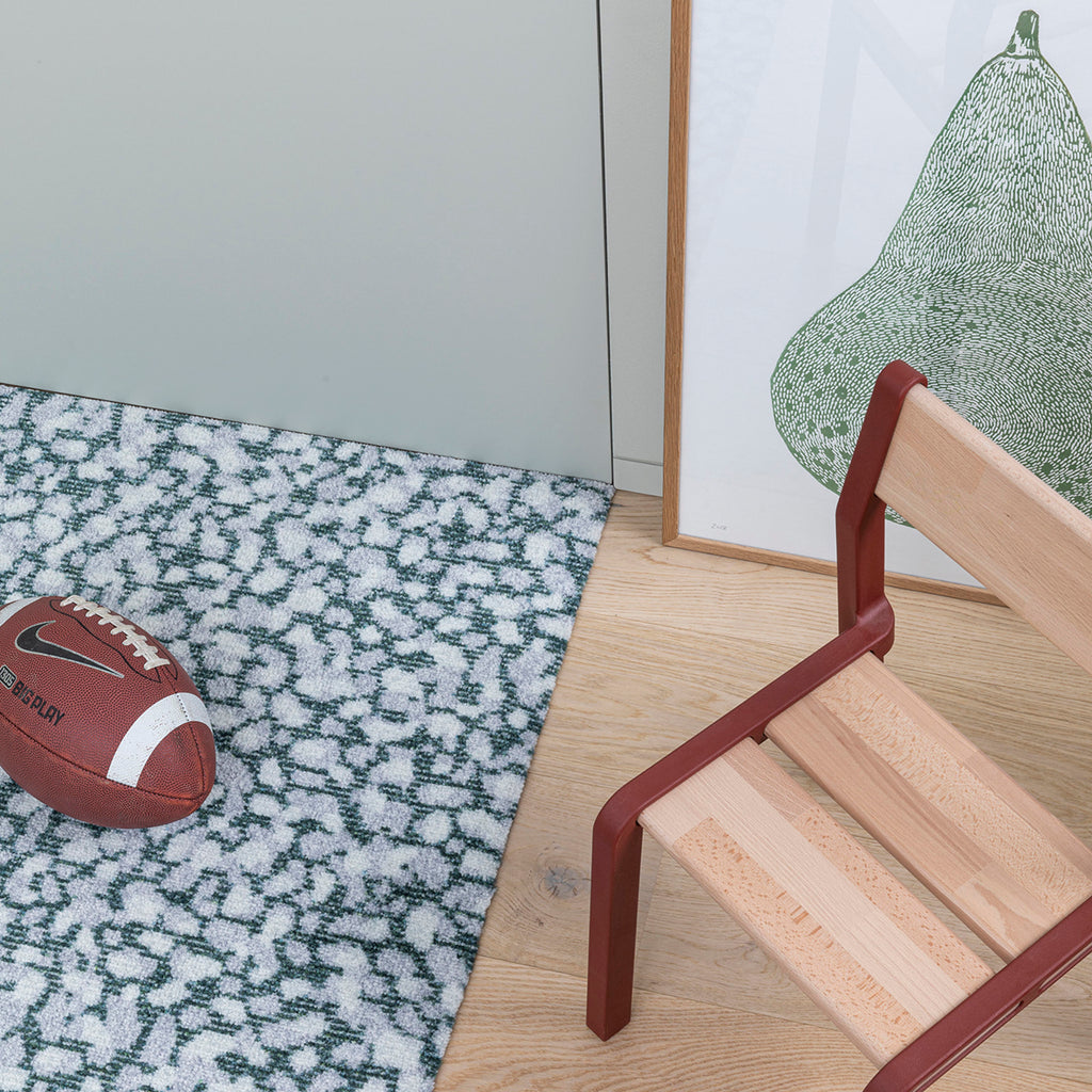 Grain Granite stone-textured doormat, styled in modern entryway with white oak floors and Scandinavian accessories.