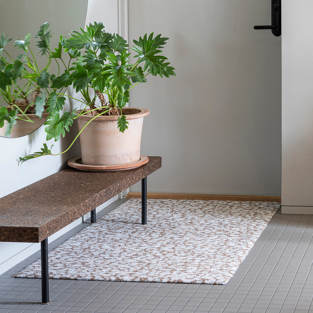 Heymat Grid Sandstone doormat, slip-resistant and washable, styled in modern entryway with small square grey tile floor and potted plant