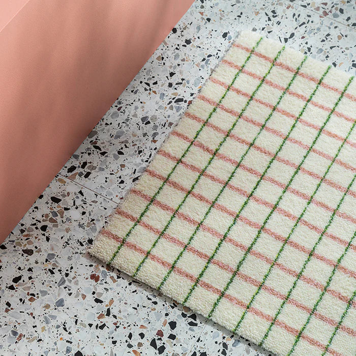 Heymat Grid Lime Candycane doormat with square grid design, styled in modern entryway with pink accents and terrazzo floor.