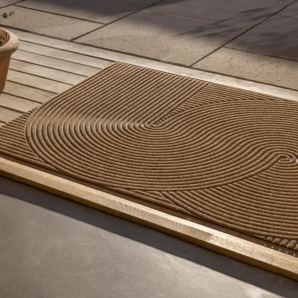 Large Heymat Sand Outdoor mat styled in a minimalist, Scandinavian terrace with natural wood and concrete.