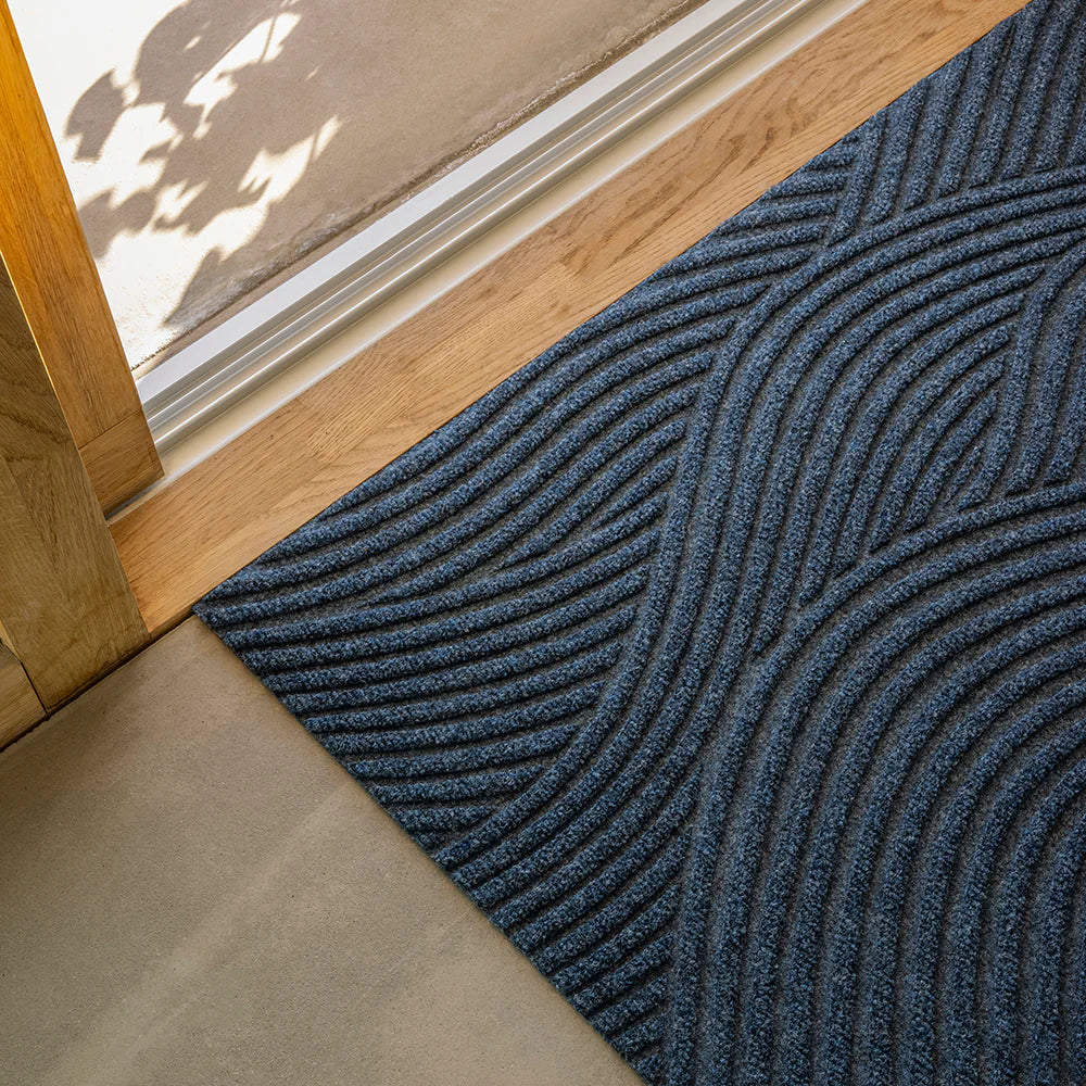 Close up image of Heymat Sjo doormat with sea-inspired wave pattern, styled in coastal-inspired entryway with natural décor.