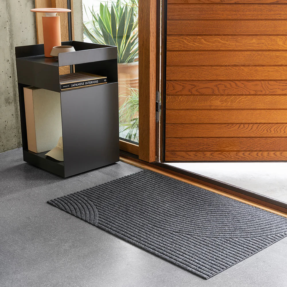 Heymat Stein doormat with stone-inspired pattern, styled in minimalist entryway with natural wood and plants