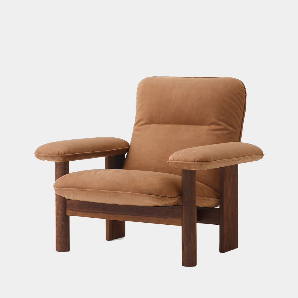 Audo Copenhagen Brasilia Lounge Chair in dark stained oak with Dunes Camel leather upholstery, highlighting its sculptural form against a neutral background.