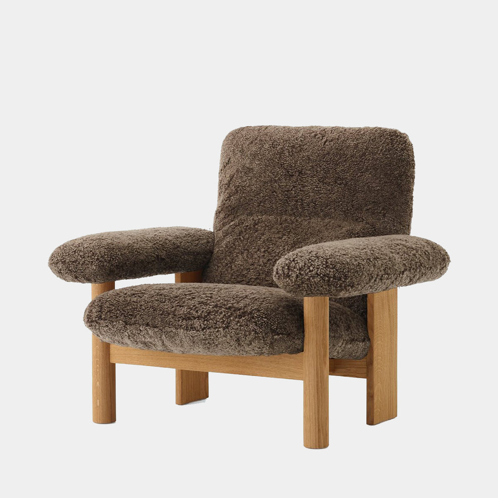 Audo Copenhagen Brasilia Lounge Chair in walnut with Sheepskin Root upholstery, emphasizing its rich texture and organic silhouette on a neutral background.