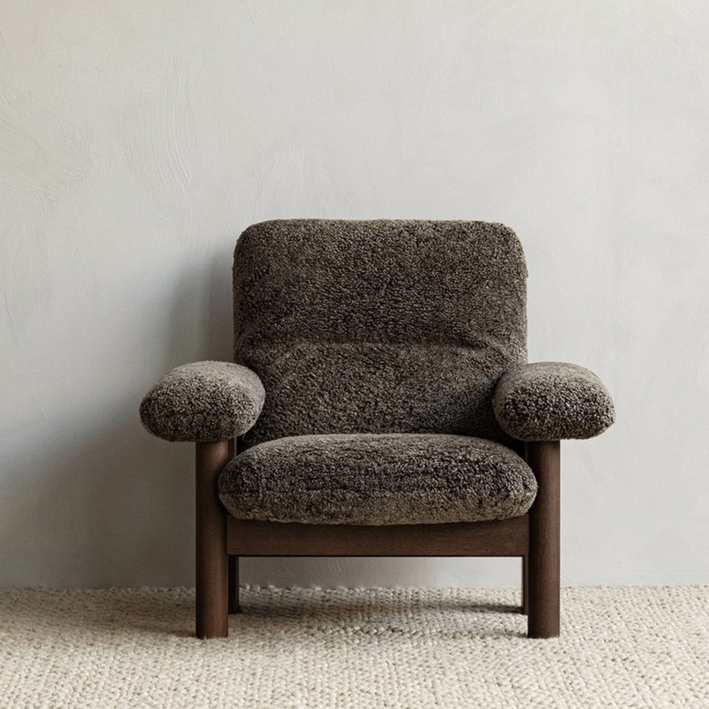 Brasillia Lounge chair in sheepskin root styled on textured rug against neutral background.