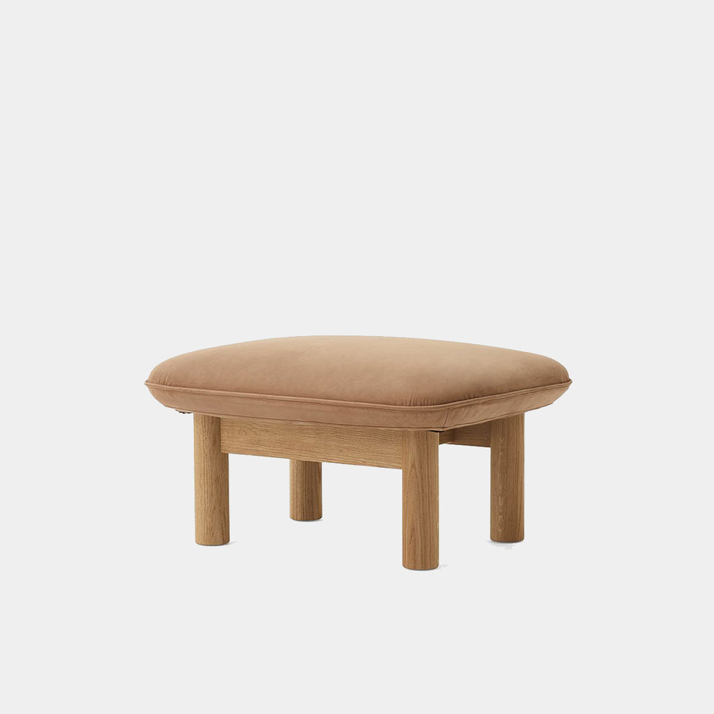 Audo Copenhagen Brasilia Ottoman in dark stained oak with Dunes Camel leather upholstery, shown on a neutral background.