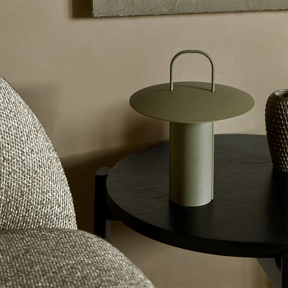 Ray Portable Table Lamp in Olive by Audo Copenhagen on a shelf — modern portable LED lamp adding soft, ambient light.