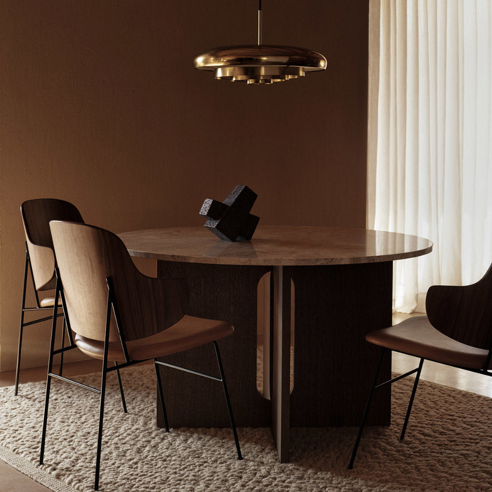Resonant Pendant by Audo Copenhagen suspended above a dining table — warm brass finish casting ambient light.