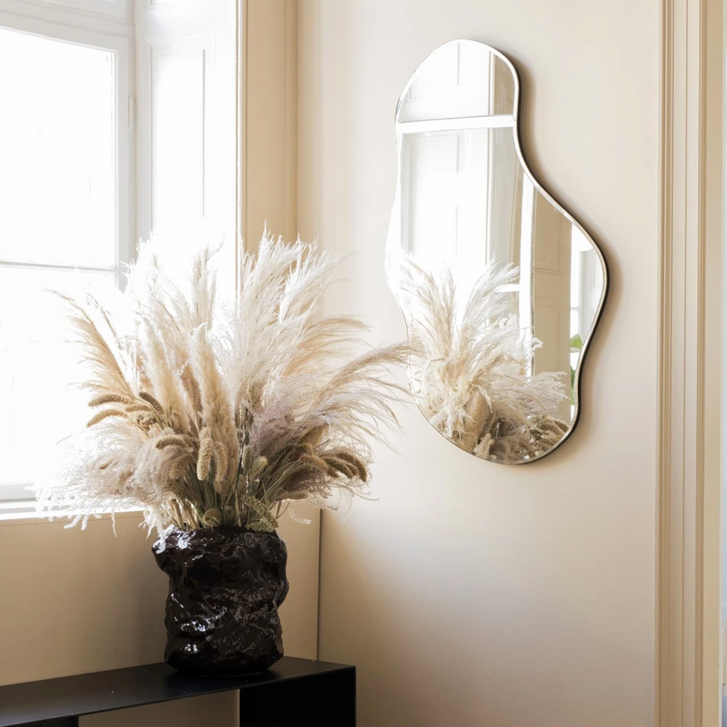 Pond Mirror Large in dark chrome styled in a modern living space reflecting soft natural light and furnishings.