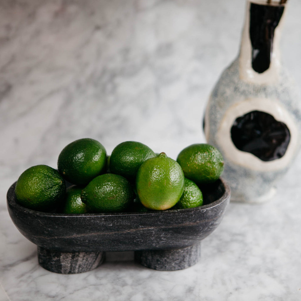 Alza Bowl in Black Marble displayed on marble countertop as a sculptural catch-all holding limes