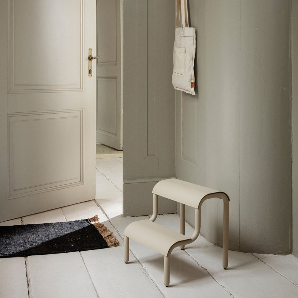 Black Block Mat with natural fringe in minimalist interior beside Ferm Living Up Step bench.