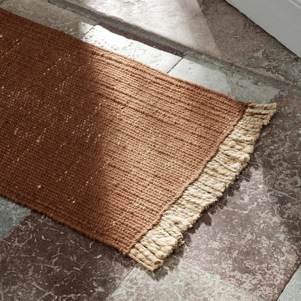 Bright Blue Block Mat with natural fringe on stone floor under under natural light.