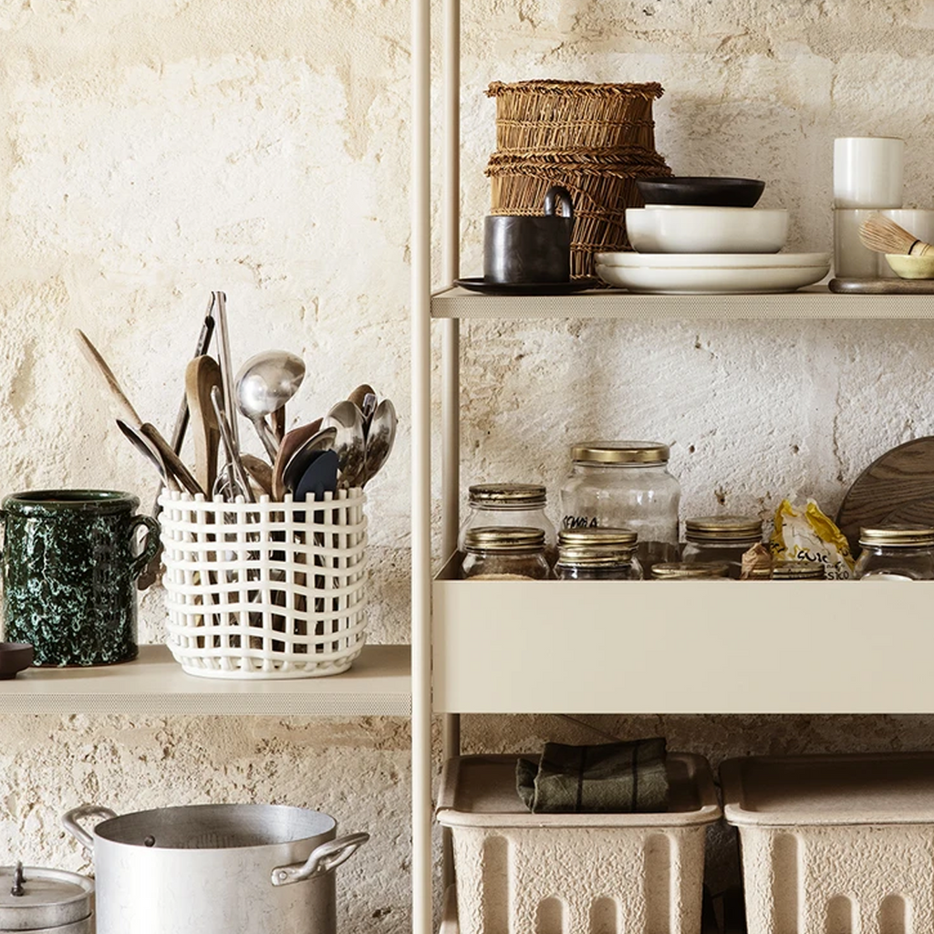 Ferm Living Ceramic Basket Large in Off-White — glazed ceramic basket used for kitchen utensil storage on open shelving, styled against a textured plaster wall with earthy neutral tones
