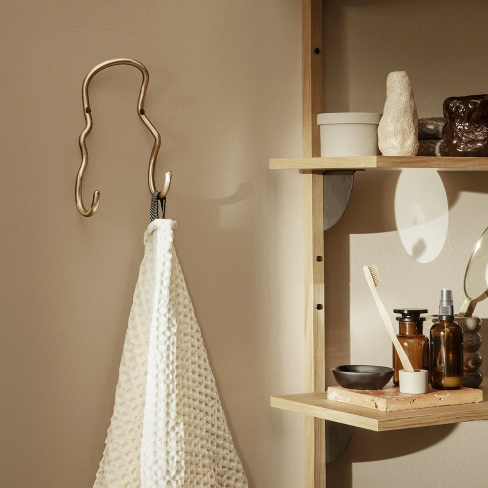Ferm Living Curvature Double Hook in Brass shown in natural light holding waffle towel.