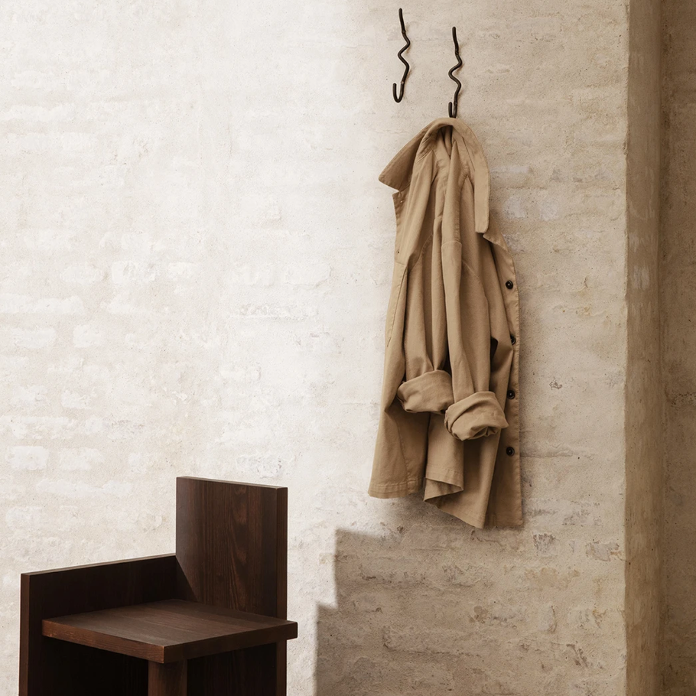 Curvature Hook in Black Brass by Ferm Living styled with hanging jacket — modern handcrafted wall hook with sculptural form.
