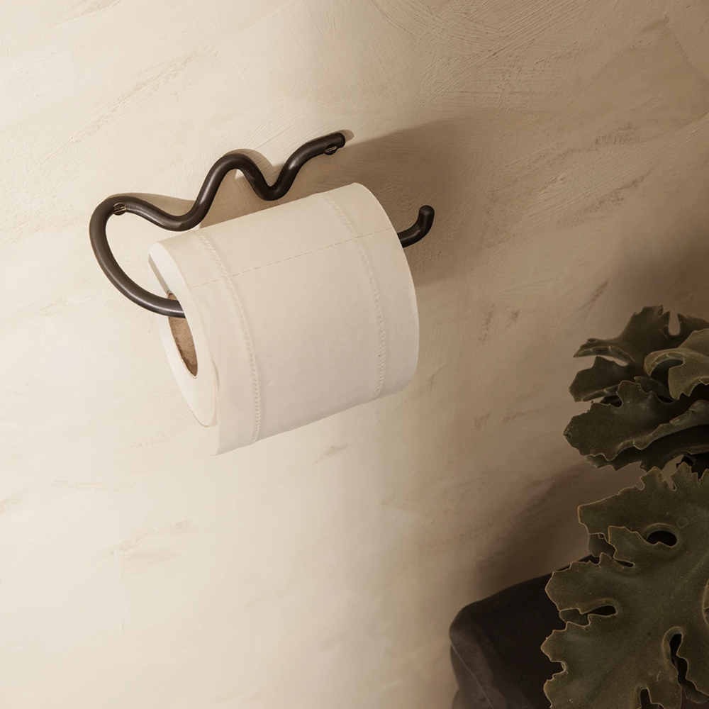 Curvature Toilet Paper Holder in Black Brass by Ferm Living styled in contemporary bathroom — sculptural, handcrafted wall fixture.