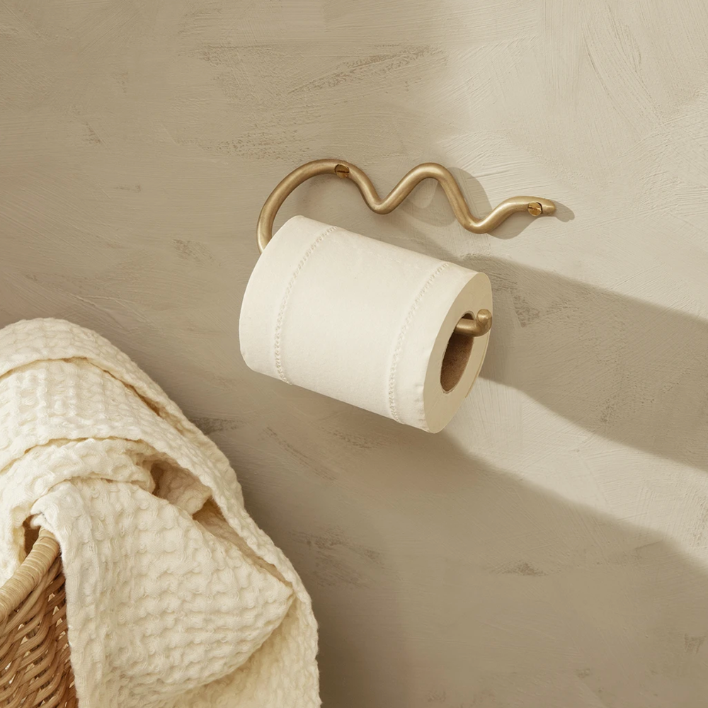 Curvature Toilet Paper Holder in Brass by Ferm Living styled in contemporary bathroom — sculptural, handcrafted wall fixture.
