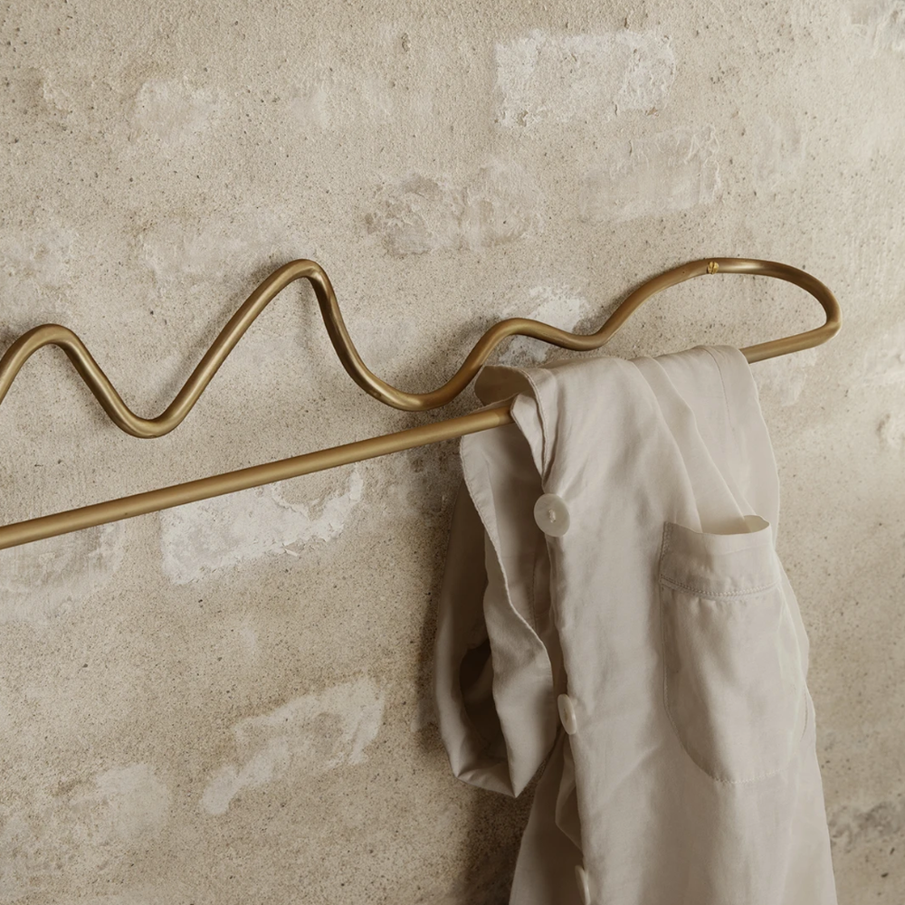 Close-up of curved form and matte surface on Ferm Living Curvature Towel Hanger — hand-formed solid brass craftsmanship.