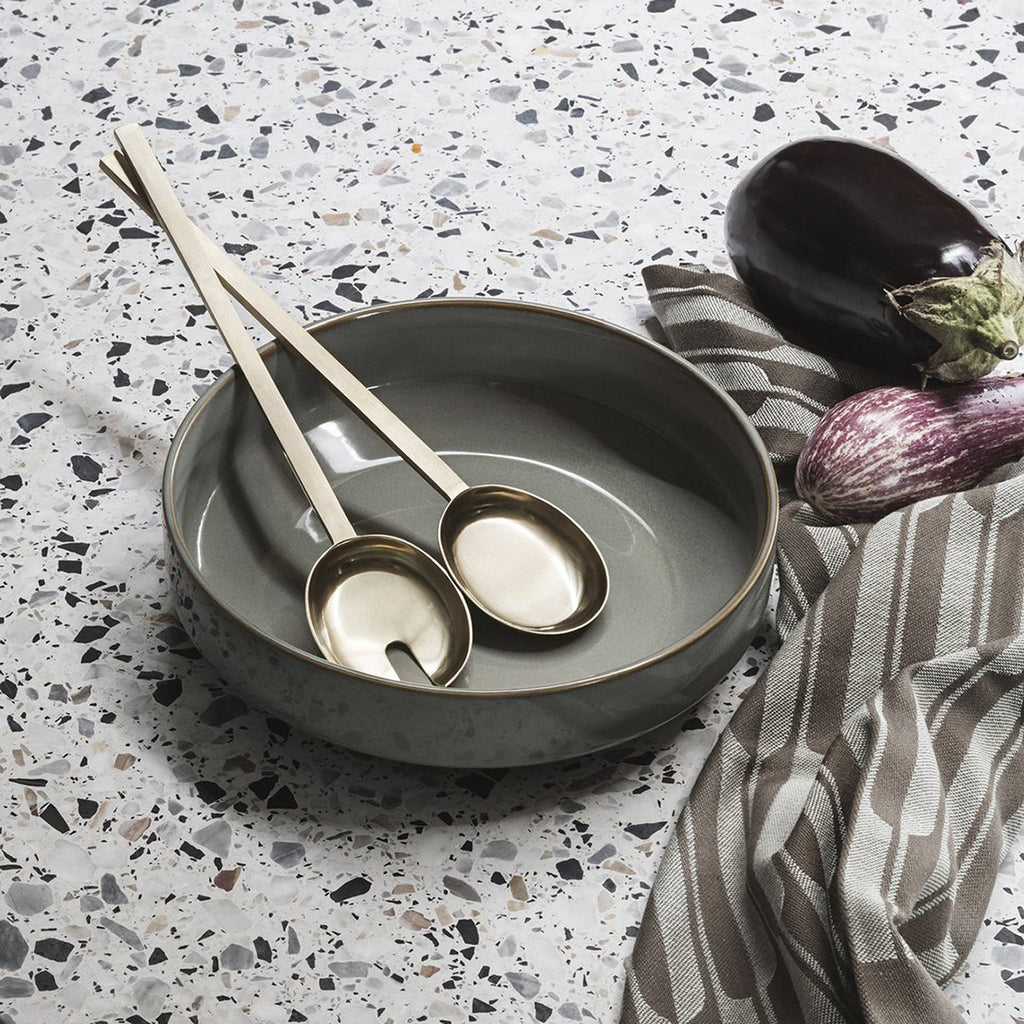 Fein Salad Servers by Ferm Living resting on a terrazzo dining table beside a modern serving bowl.”