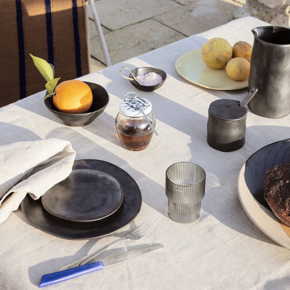 Flow Plate Black stacked with matching bowls — modern monochrome dinnerware by Ferm Living