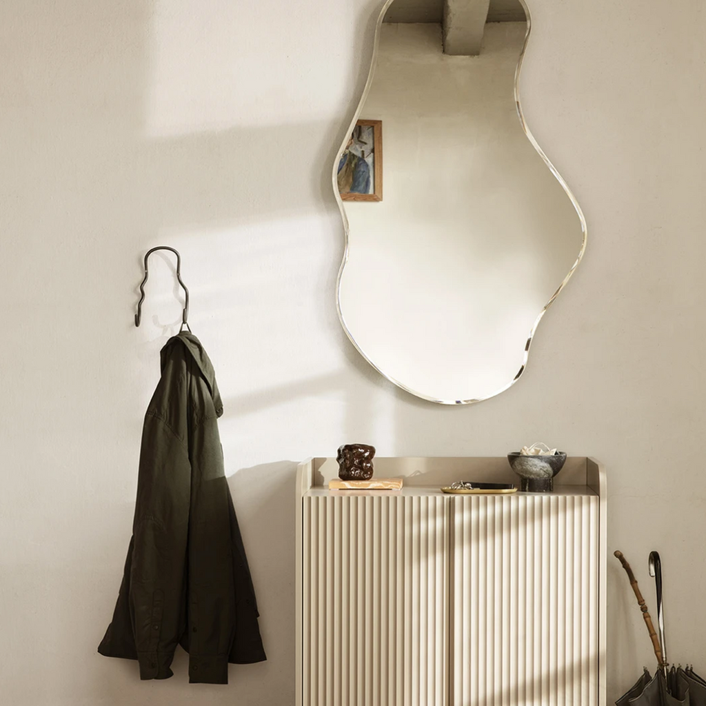 Pond Mirror Large in brass styled above a console table with sculptural décor in a warm, minimalist interior
