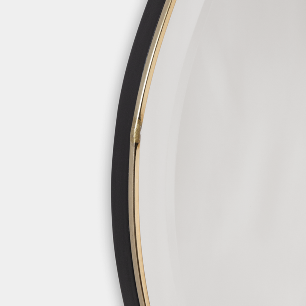 Close-up of Pond Mirror Small in brass showing reflective glass edge and smooth curved metal trim.