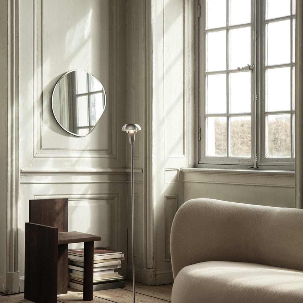 Ferm Living Pond Mirror Small in dark chrome with fluid shape, shown mounted vertically in a bright interior.