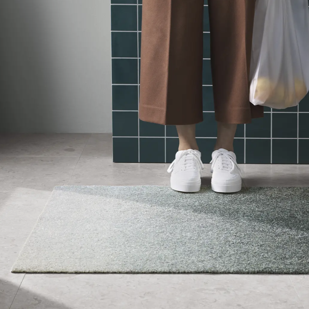 Heymat Dis in color Ocean, washable and slip resistant doormat styled on concrete floor