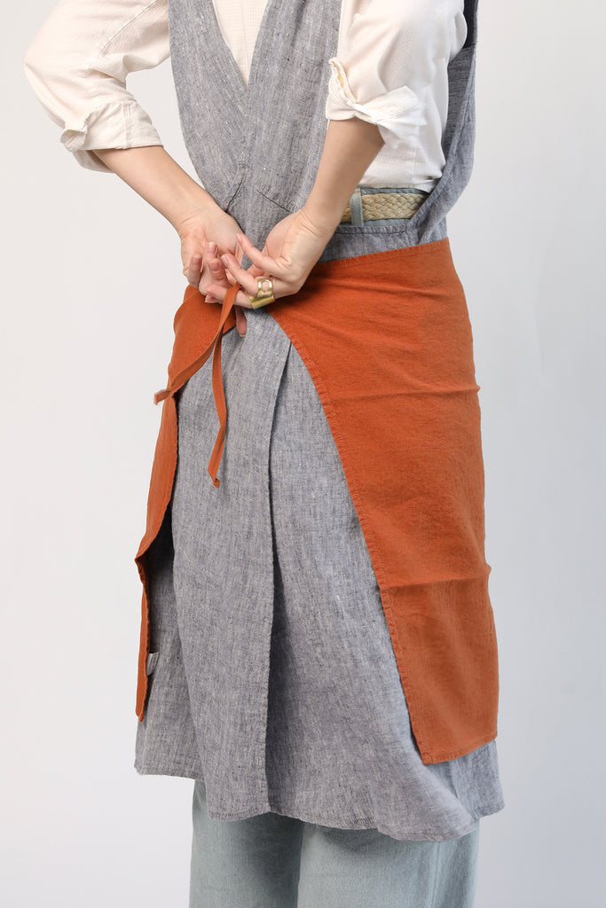 Linge Particulier linen dish towel in Sienna shown tied around the waist as an impromptu apron, highlighting its soft washed texture and versatile cotton ties.