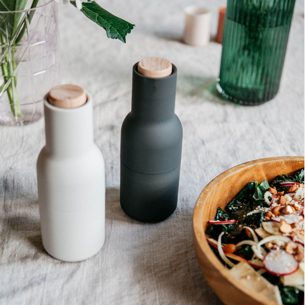 Audo Copenhagen Bottle Grinders in off-white and carbon with beech tops, minimalist Scandinavian salt and pepper mills styled on a dining table