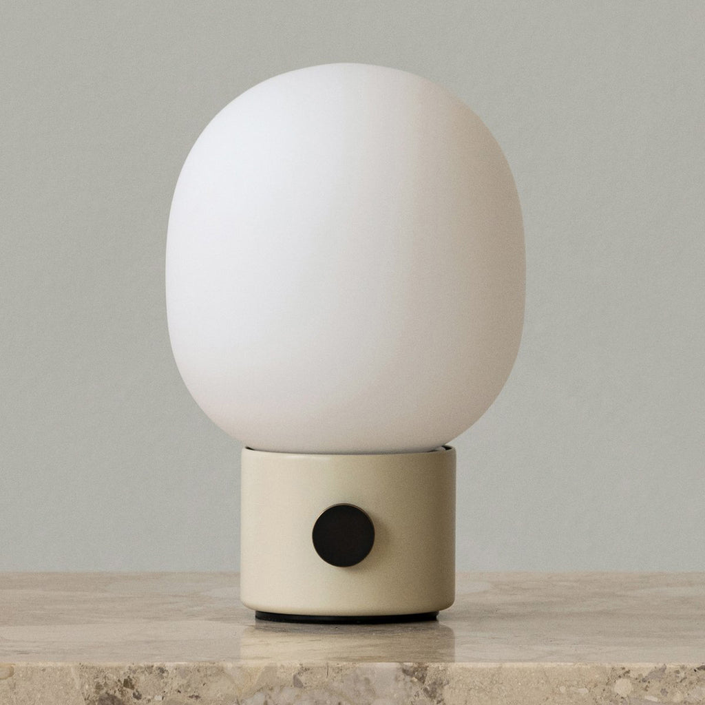 Audo Copenhagen JWDA Portable Lamp in Alabaster White with frosted glass shade and black dimmer knob, shown on a neutral background atop a marble surface.