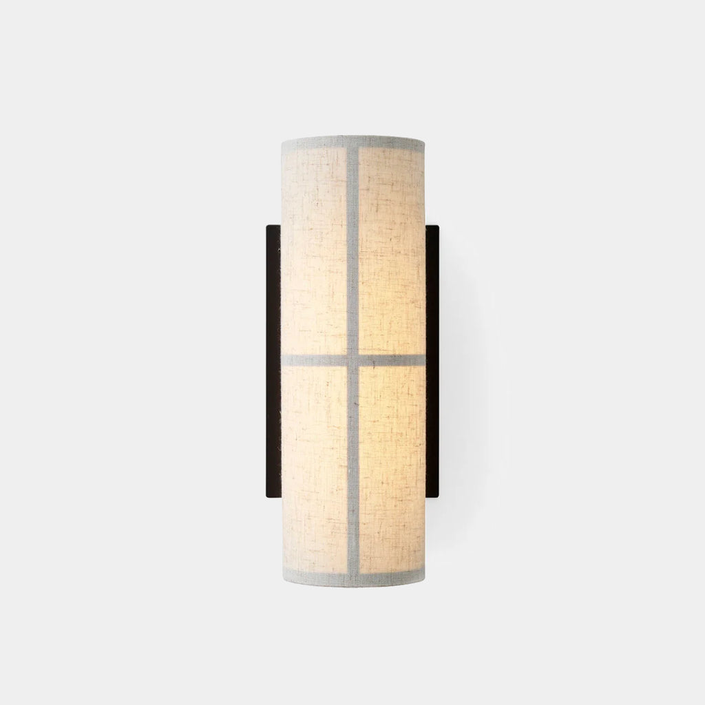 Hashira Wall Lamp in raw linen casting soft ambient light upward and downward through textured linen shade on neutral background