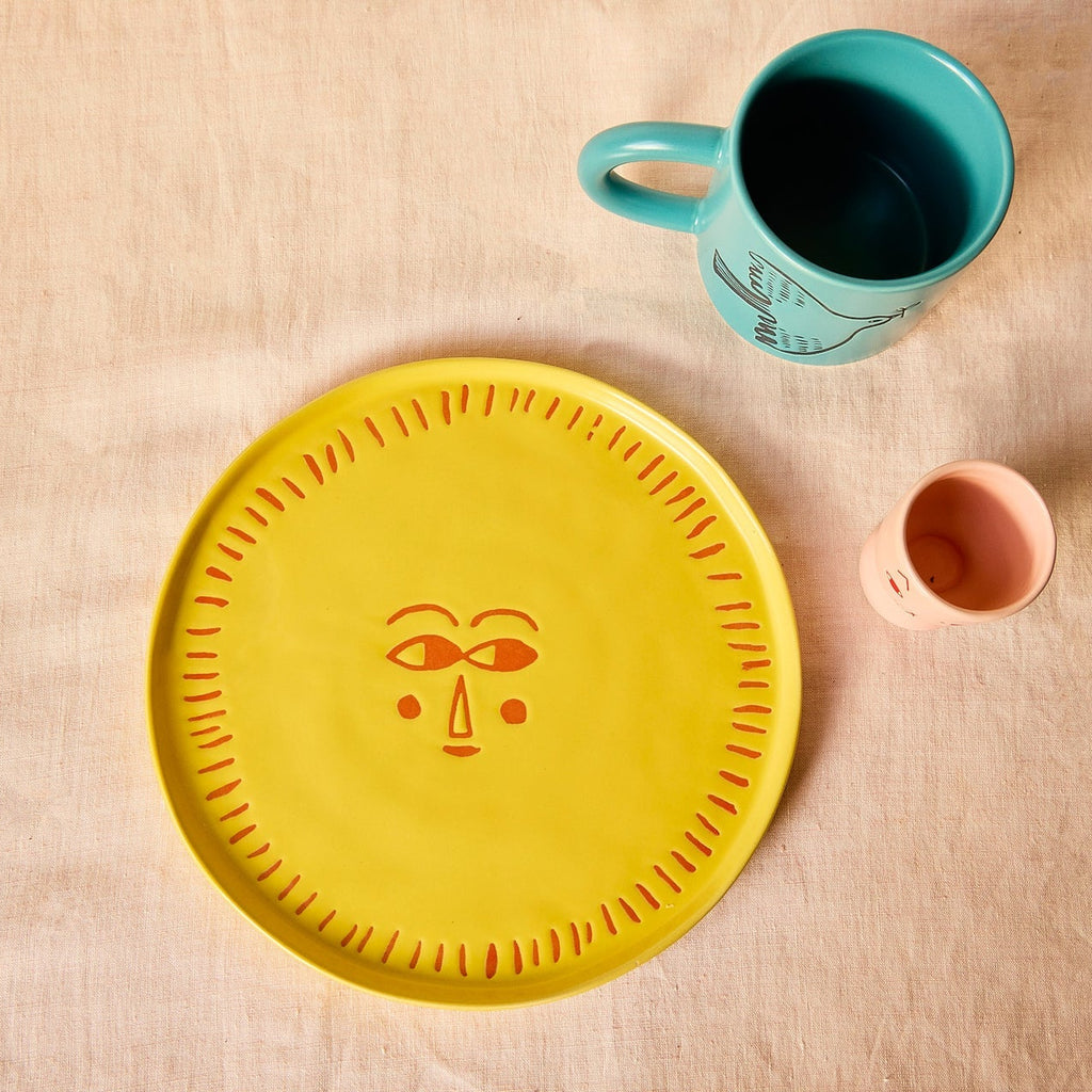 Donna Wilson Sunshine Plate styled on tablecloth with bird mug and egg cup.