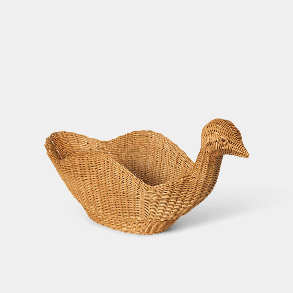 Angled view of braided rattan bird-shaped storage basket with rounded body and tail detail on a neutral background