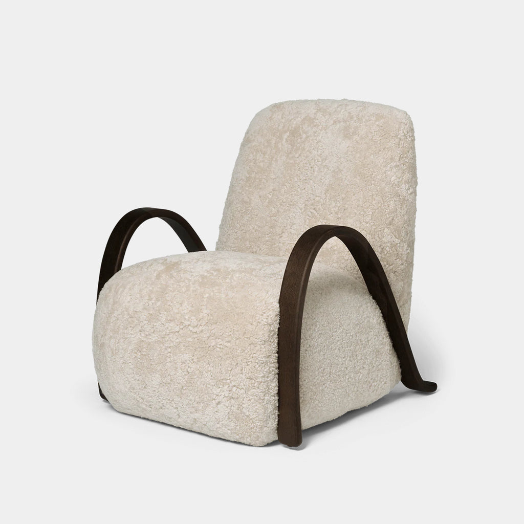 Buur Lounge Chair in Sheepskin Moonlight with curved dark oak armrests on a neutral background
