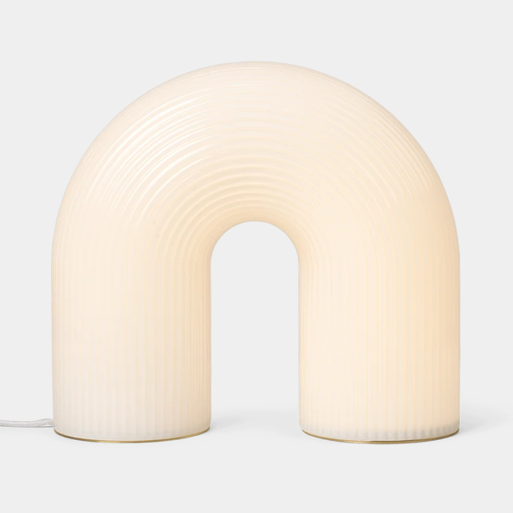 Ferm Living Vuelta Floor Lamp softly illuminated in White with arched form and rippled opal glass