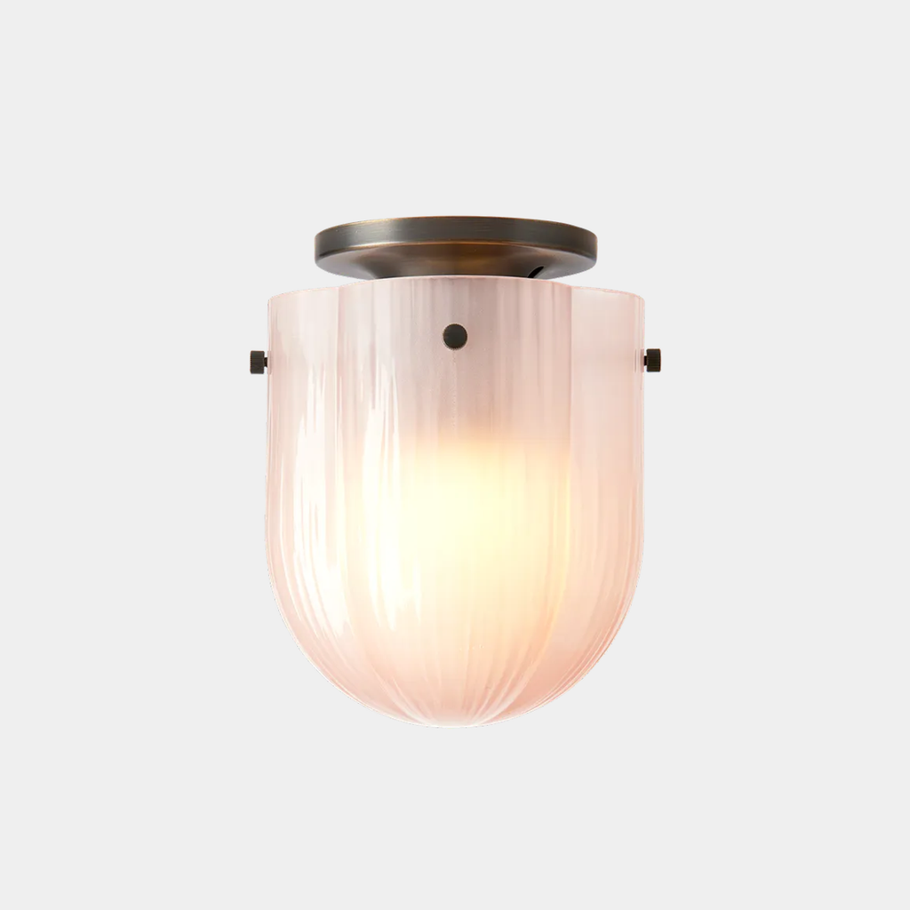 Illuminated GUBI Seine Ceiling Lamp in Coral glass and antique brass, softly glowing on neutral background