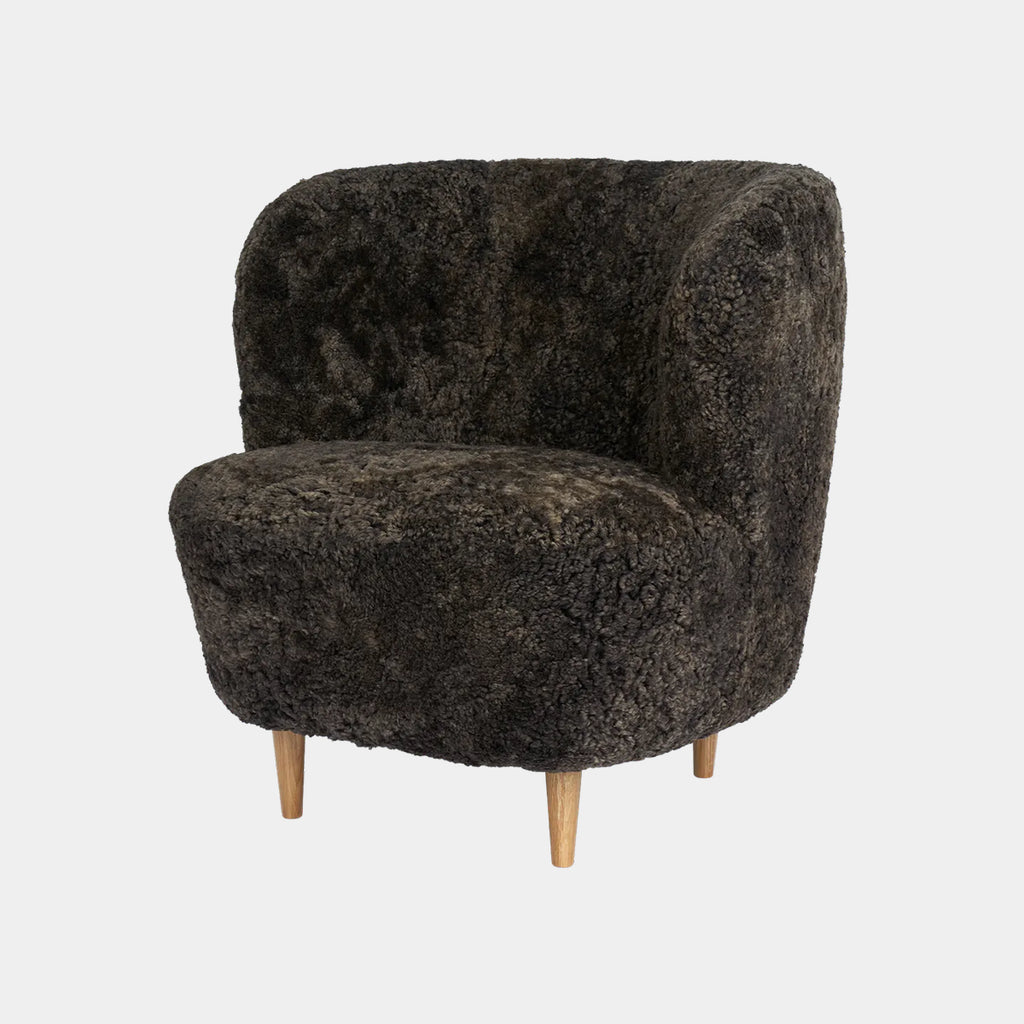 Stay lounge chair by GUBI in Skandilock sheepskin in Espresso, highlighting its sculptural organic form and flowing modern silhouette