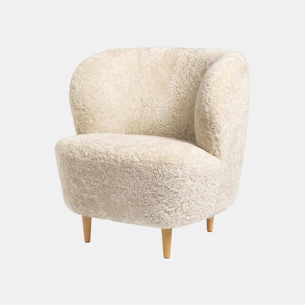 Stay lounge chair by GUBI in Skandilock sheepskin in Moonlight highlighting its sculptural organic form and flowing modern silhouette