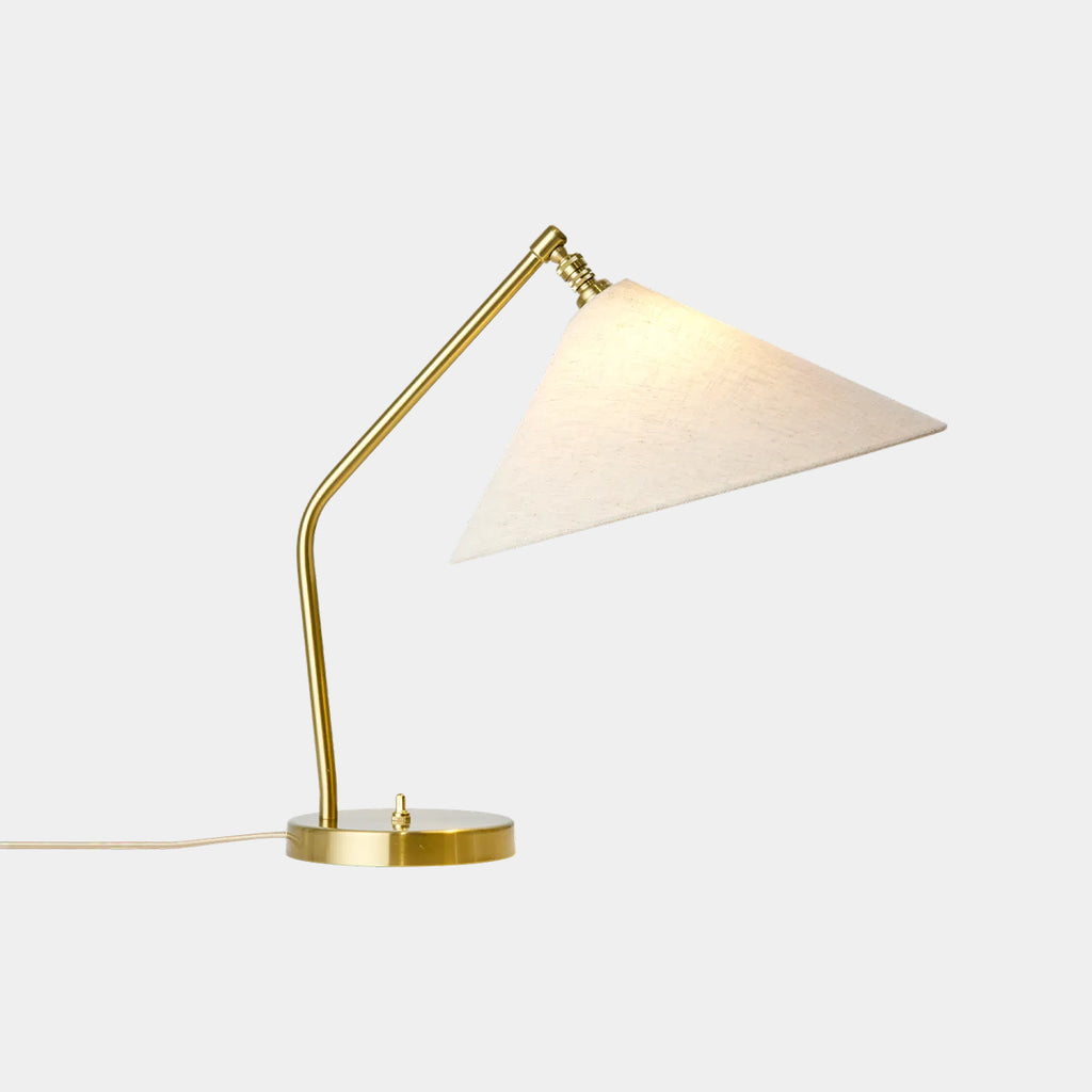 Gräshoppa Table Lamp with illuminated elongated canvas shade and polished brass base on neutral background.