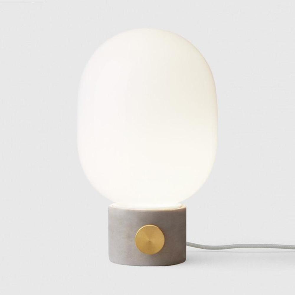 JWDA Table Lamp with concrete base shown with opal shade softly illuminated. 