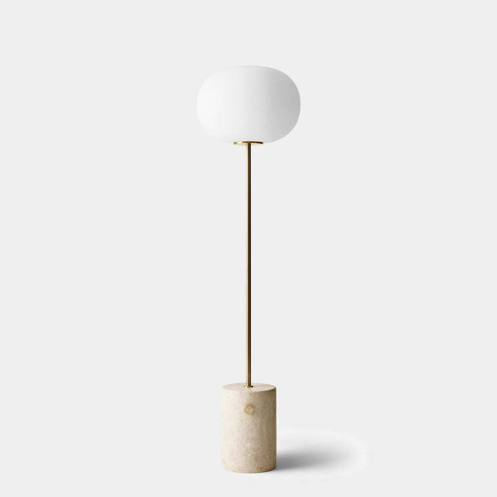Front view of JWDA Floor Lamp by Audo Copenhagen with opal glass shade and brass dimmer knob on slim stem and solid travertine base